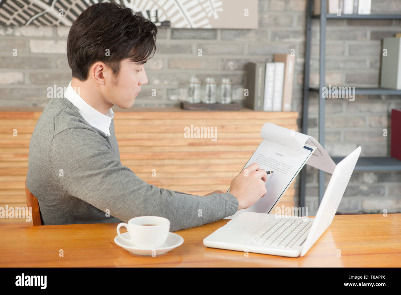 Seite Ansicht Porträt jungen Geschäftsmann hält einen Stift und Papier im Café lesen Stockfoto