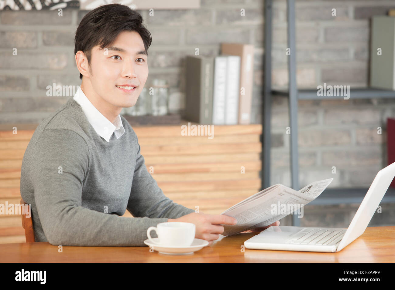 Seite Ansicht Porträt junger Geschäftsmann Betrieb Zeitung im Café lächelnd Stockfoto