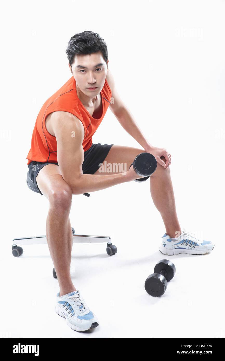 Seitenansicht des Mannes in der Sportswear sitzen und halten eine Hantel nach unten Stockfoto