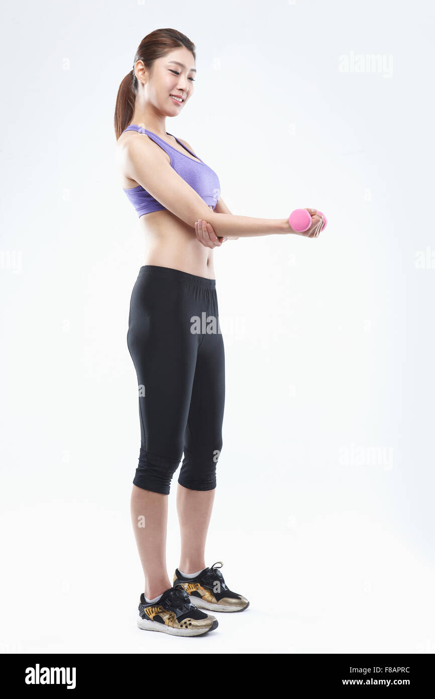 Seitenansicht der lächelnde Frau in Sportbekleidung eine Hantel nach unten halten Stockfoto
