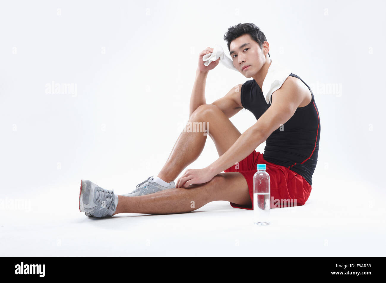 Mann in Sportbekleidung Sitzung wischte sich den Schweiß mit Wasserflasche starrte auf Vorderseite Stockfoto
