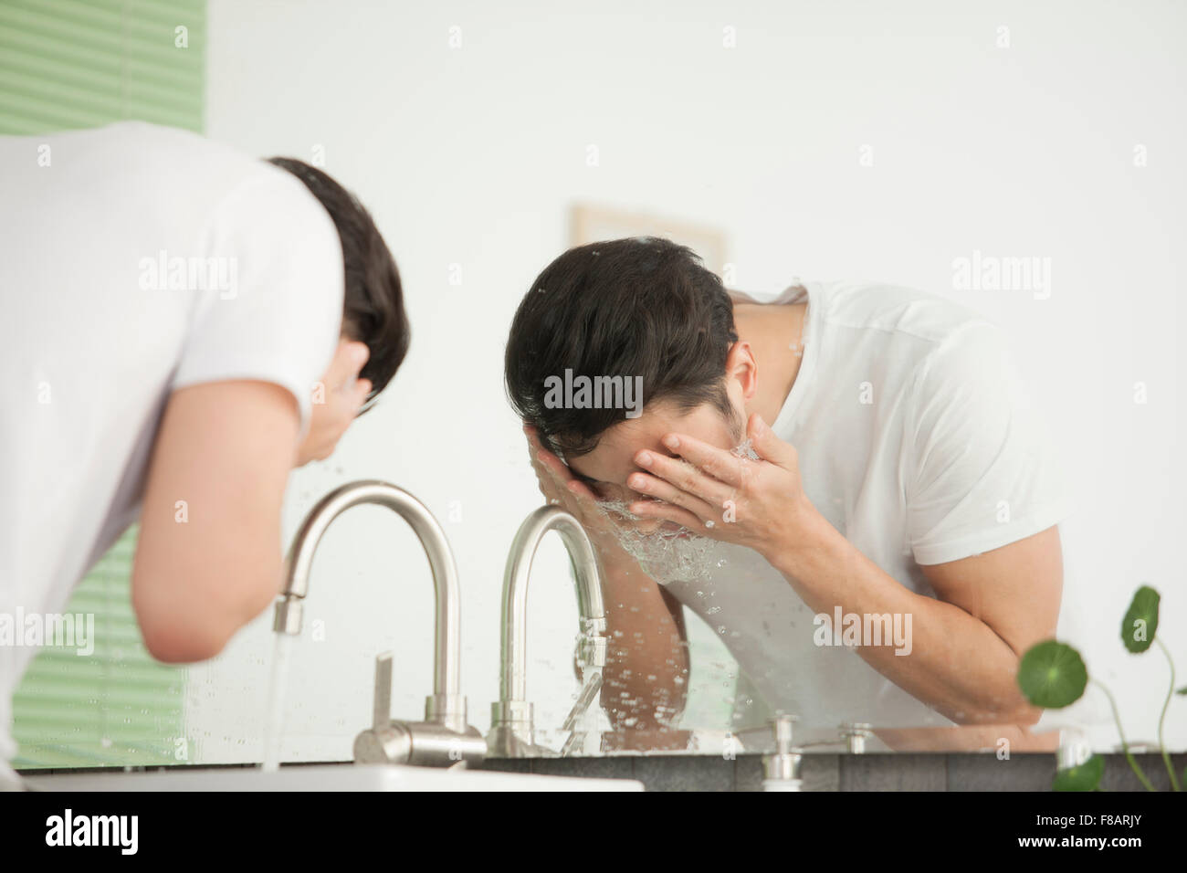 Seite Ansicht Porträt des jungen Mannes sein Gesicht am Waschbecken im Bad waschen Stockfoto