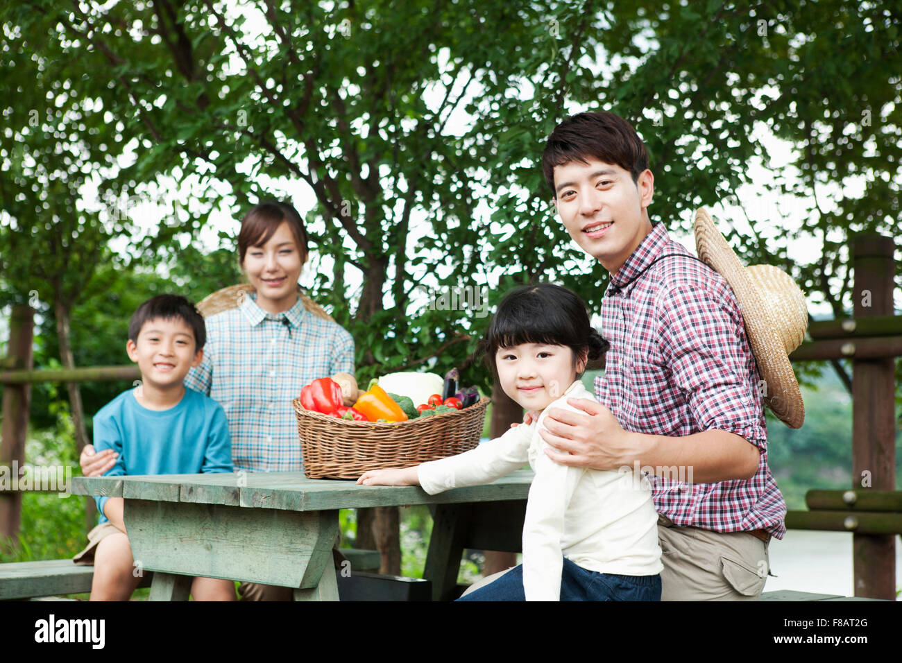 Porträt der glückliche Familie sitzen um einen Tisch im Freien mit frischem Gemüse, starrte auf Vorderseite Stockfoto