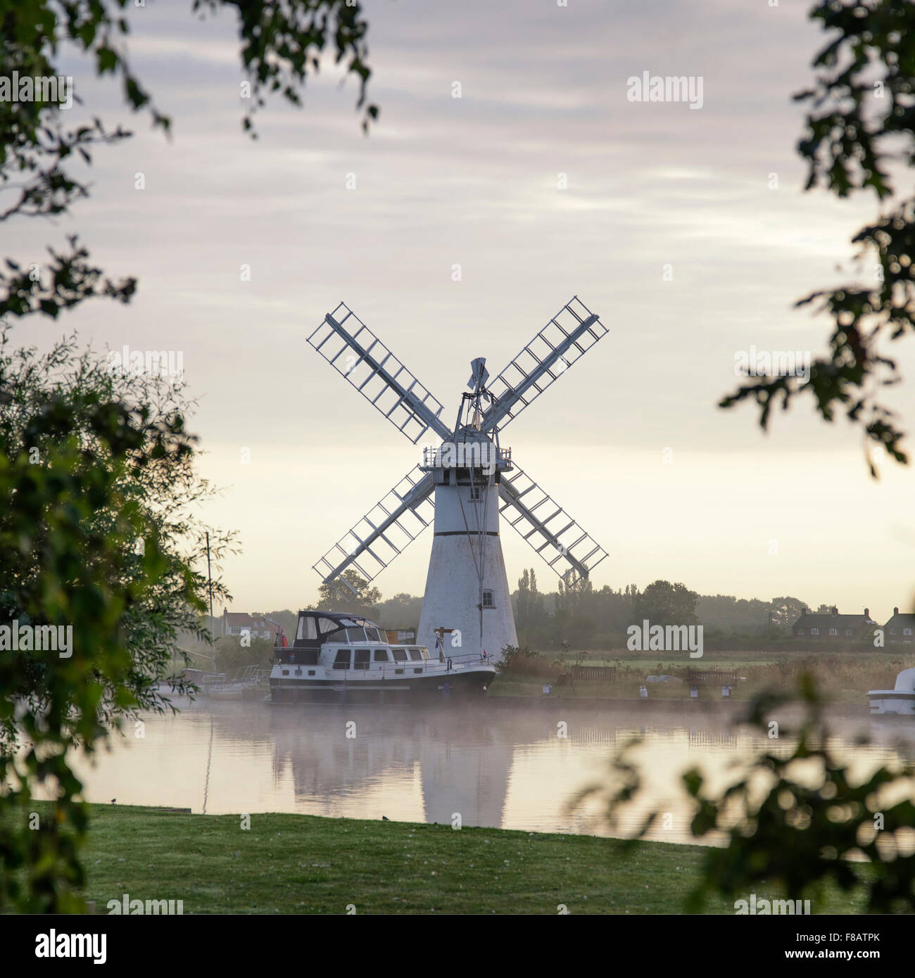 Atemberaubende Landschaft mit Windmühle und Fluss bei Sonnenaufgang am Sommermorgen Stockfoto