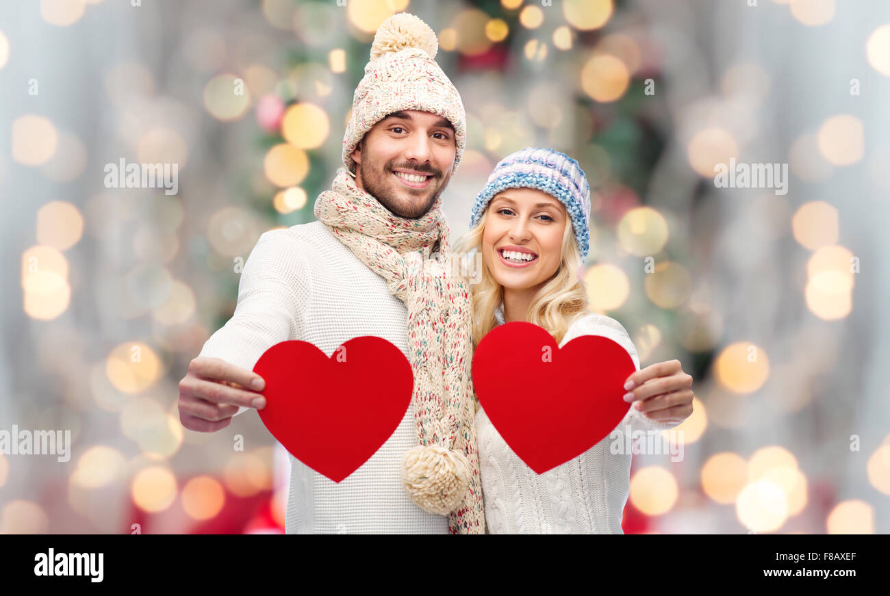 lächelnde paar in Winterkleidung mit roten Herzen Stockfoto