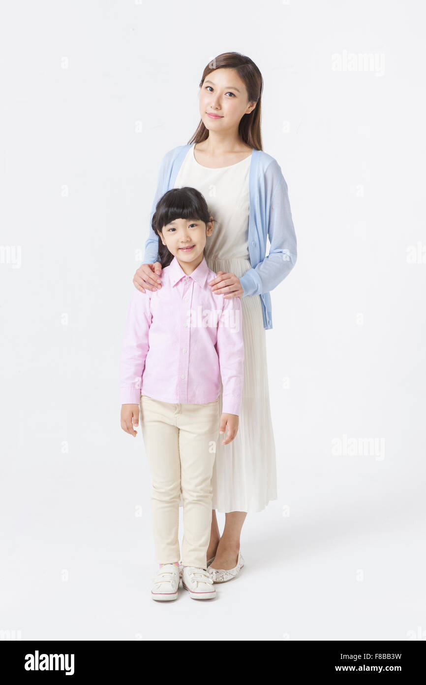 Junge koreanische Mutter stehen und legte ihre Hände auf ihre Tochter Schultern Stockfoto