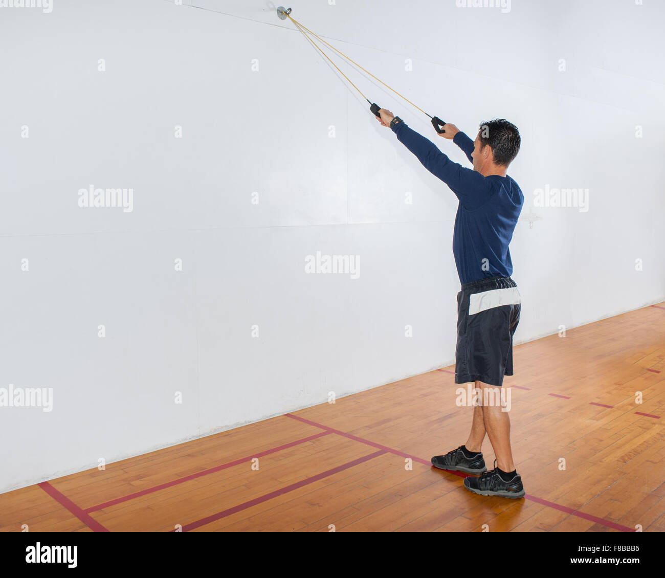 Mittleren Alter Mann Widerstand Band Übung für die Lats in Startposition auf beiden Beinen zu zeigen. Stockfoto