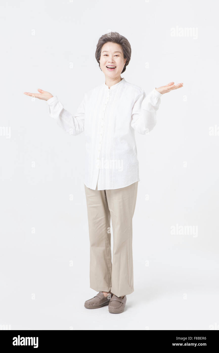 Großmutter mit kurzen Haaren in weißen Hemd Arm nach oben zu öffnen und lächelnd Stockfoto
