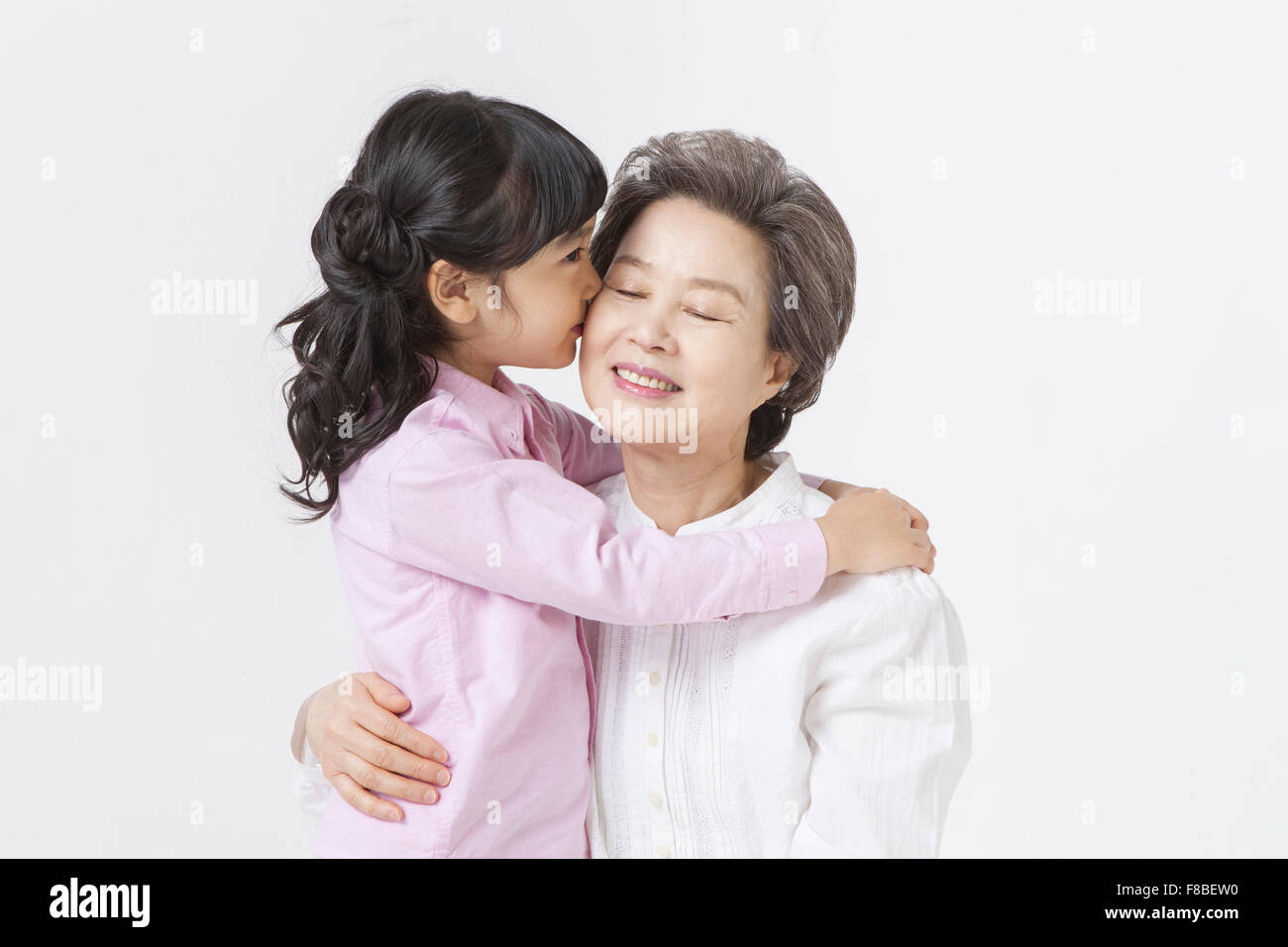 Küssen zu ihrer Großmutter Enkelin Stockfoto