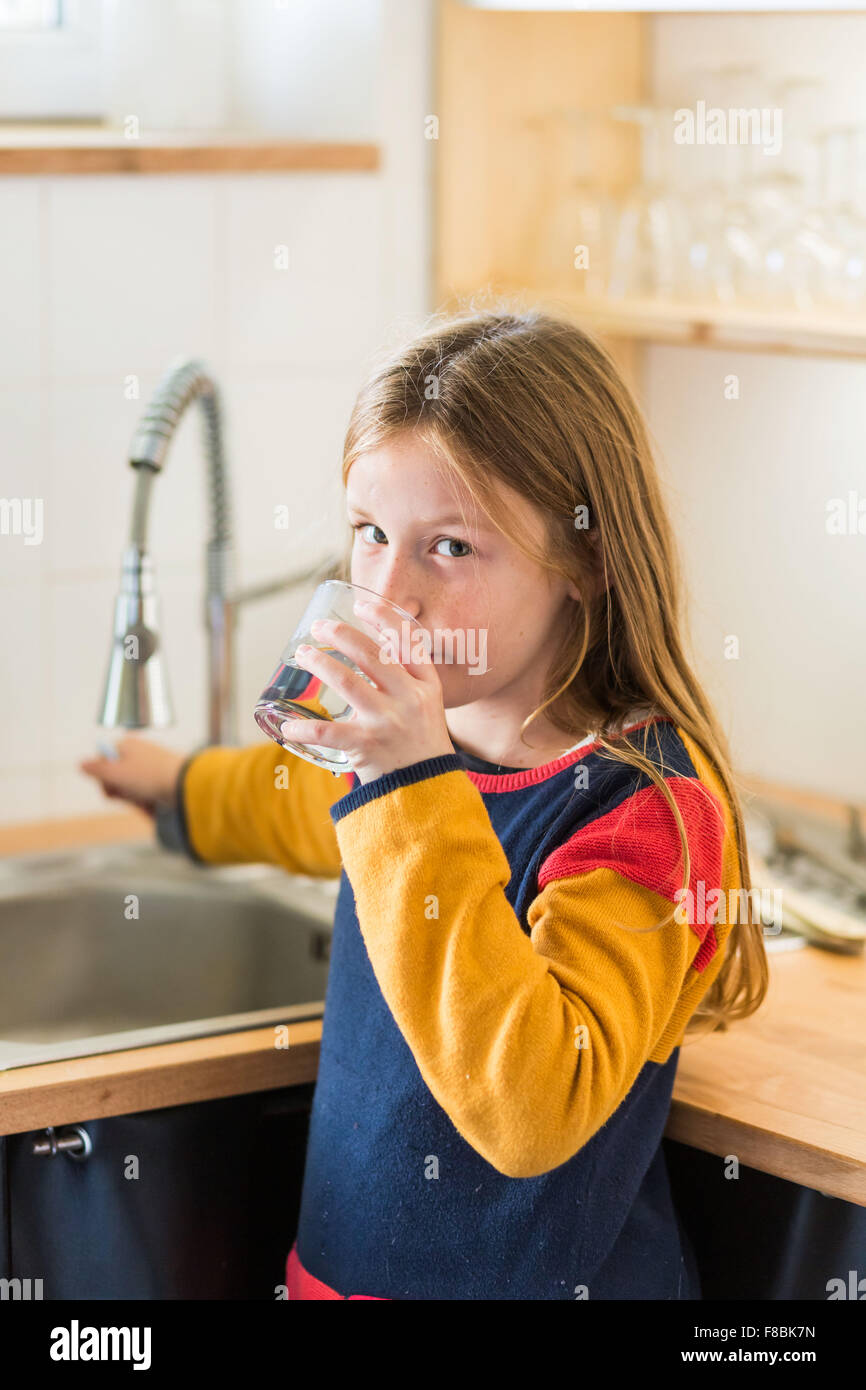 9 Jahre altes Mädchen trinken Wasser aus dem Wasserhahn. Stockfoto