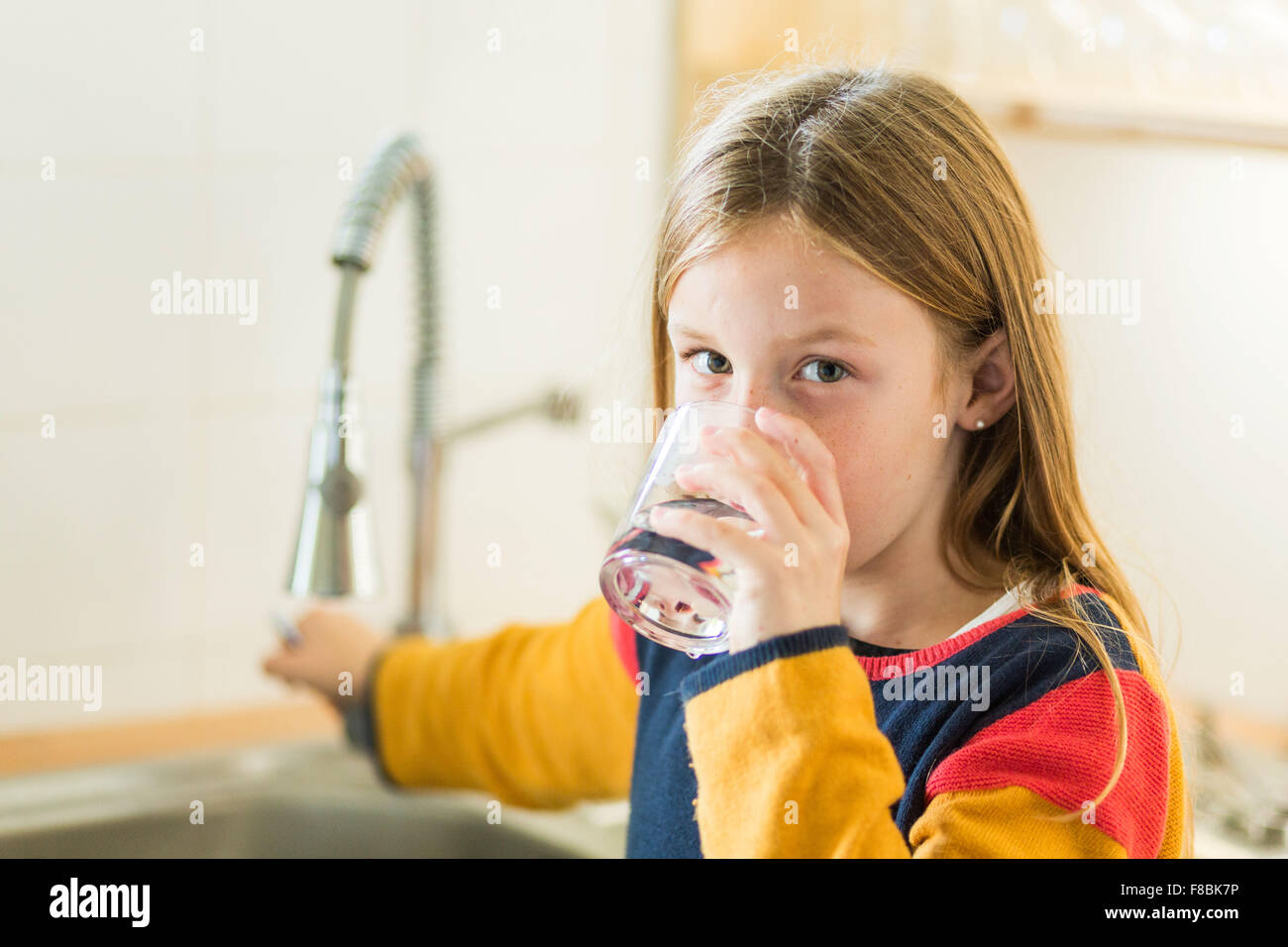 9 Jahre altes Mädchen trinken Wasser aus dem Wasserhahn. Stockfoto