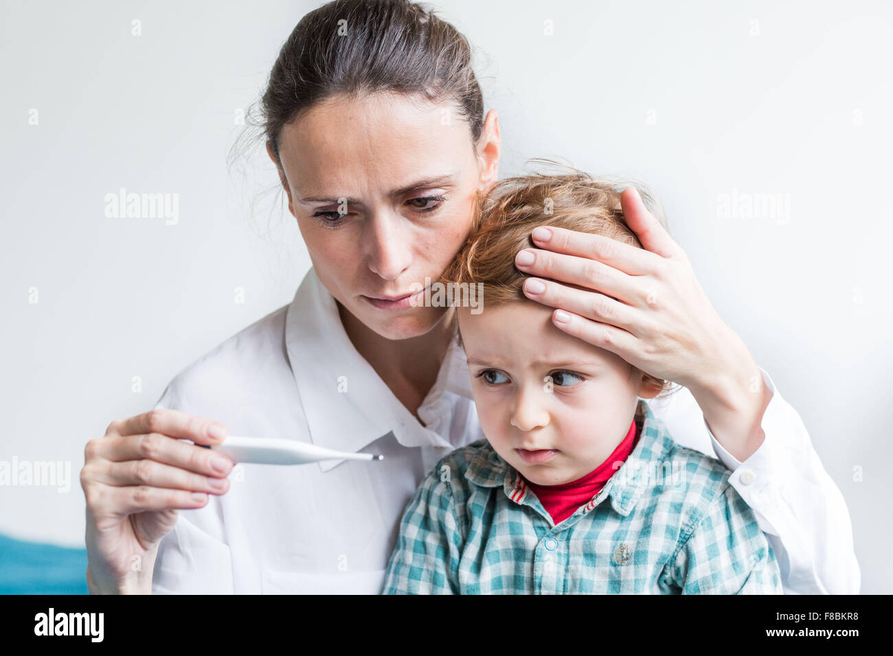 Mutter, überprüfen die Temperatur ihrer 2-jähriger Junge mit einem digitalen Thermometer. Stockfoto