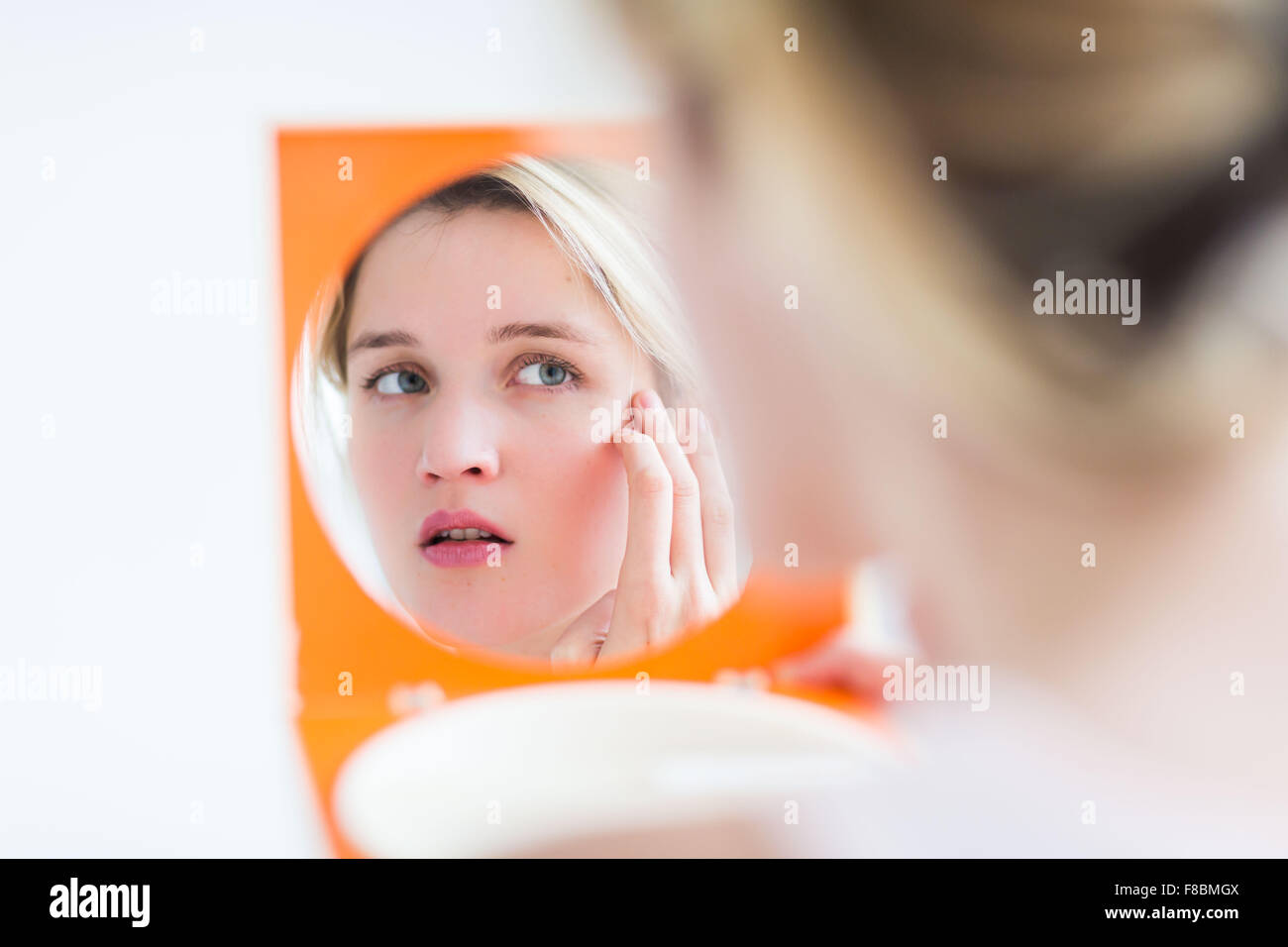 Frau ihr Gesicht im Spiegel zu überprüfen. Stockfoto