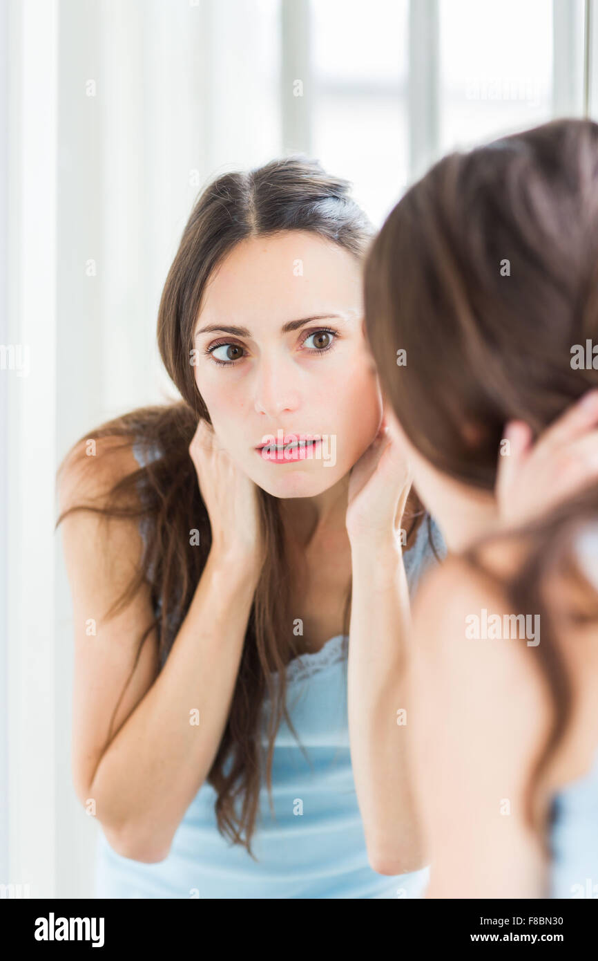 Frau ihr Gesicht im Spiegel zu überprüfen. Stockfoto