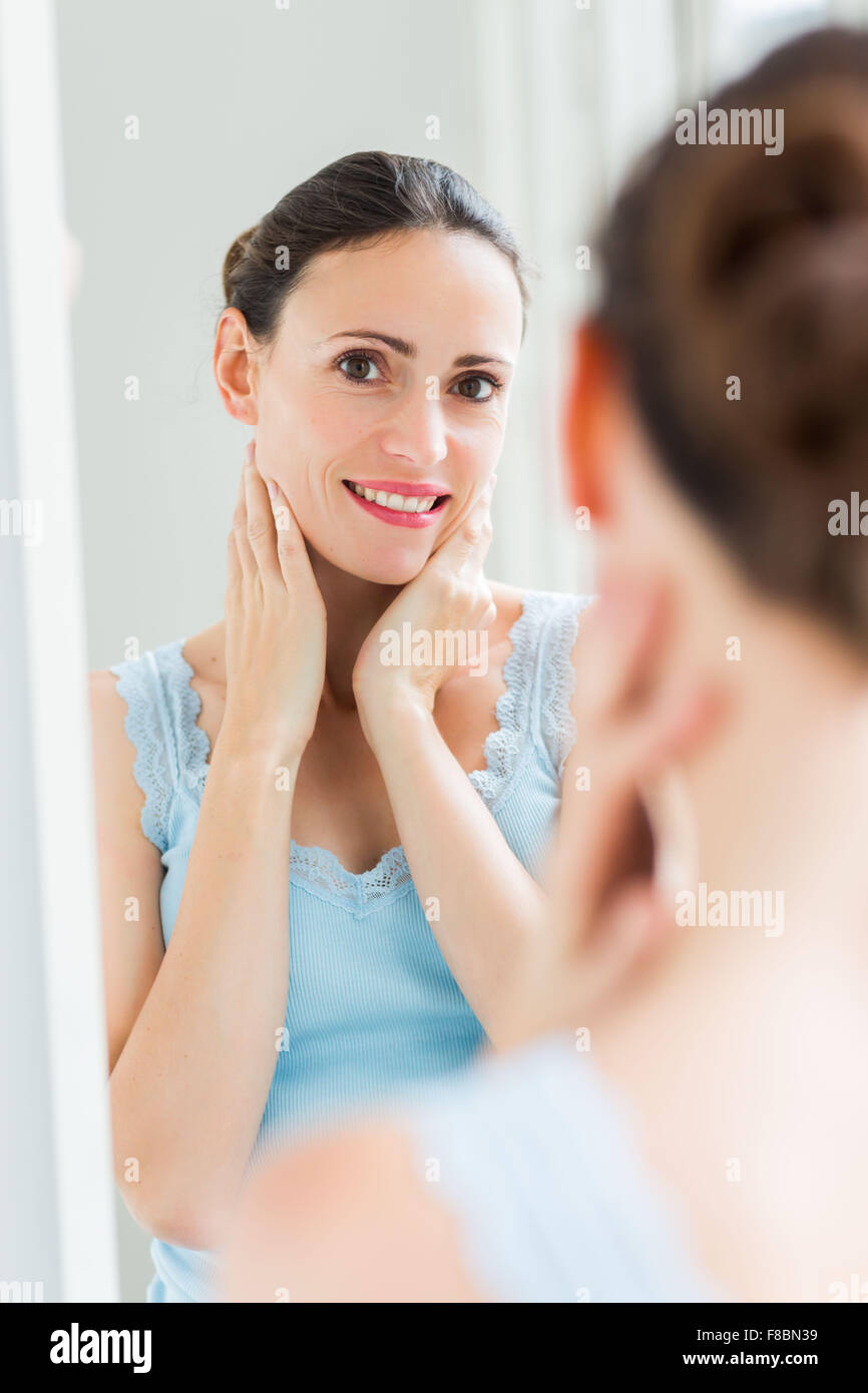 Frau ihr Gesicht im Spiegel zu überprüfen. Stockfoto