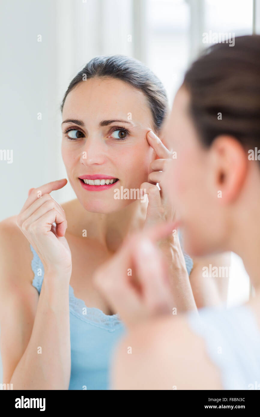 Frau ihr Gesicht im Spiegel zu überprüfen. Stockfoto