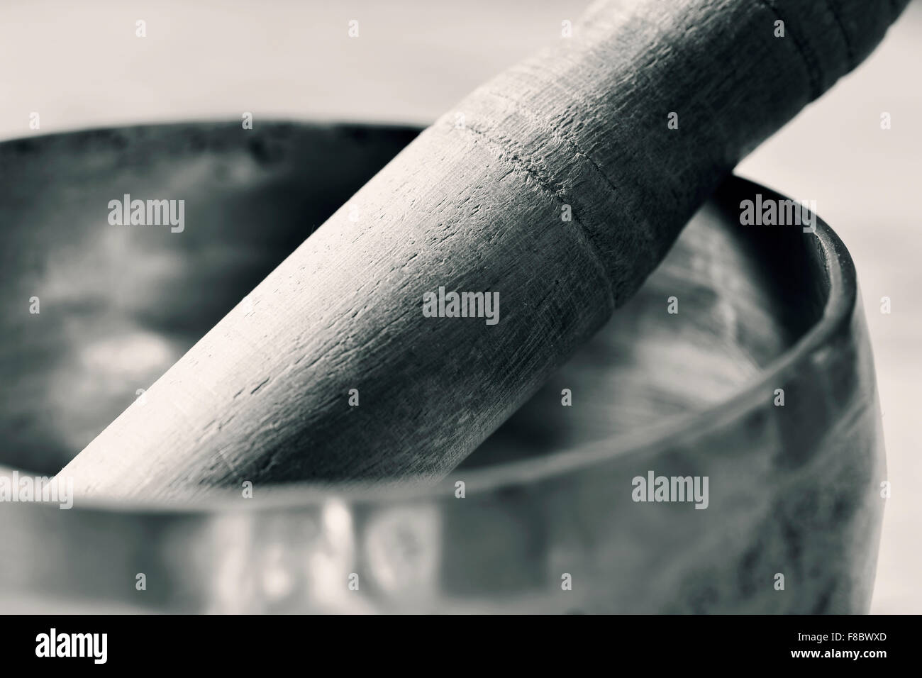 Nahaufnahme von einer tibetischen Klangschale mit seiner Holzhammer in duotone Stockfoto