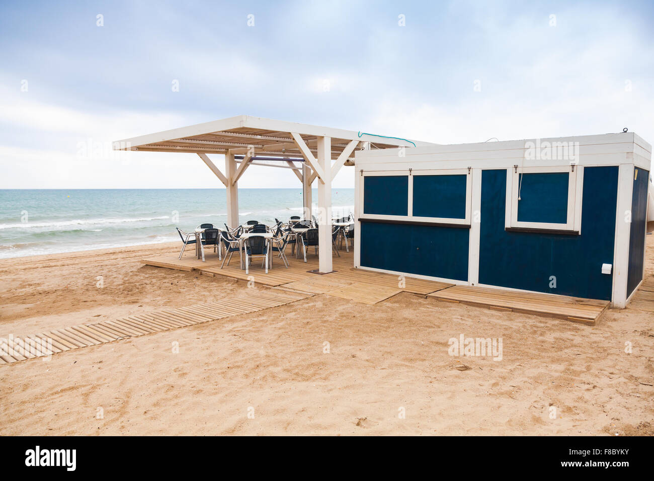 Leere offene Leertaste mit Holzboden und Metall Sessel auf dem sandigen Strand, Mittelmeerküste, Spanien Stockfoto