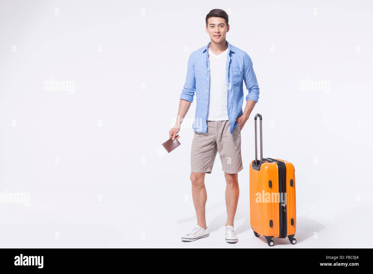Mann im casual-Outfits stehen mit seiner Hand in der Tasche hält seinen Pass mit einem Flugticket und stand neben seinem Stockfoto