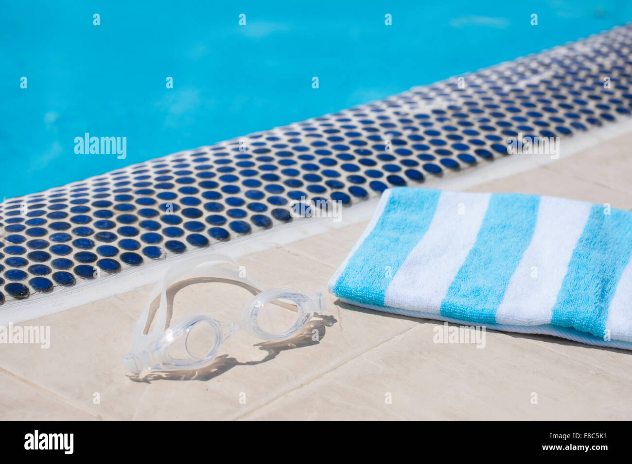 Handtuch und Schwimmen Brille auf Fliesenboden mit dem Hintergrund von Schwimmbad Stockfoto