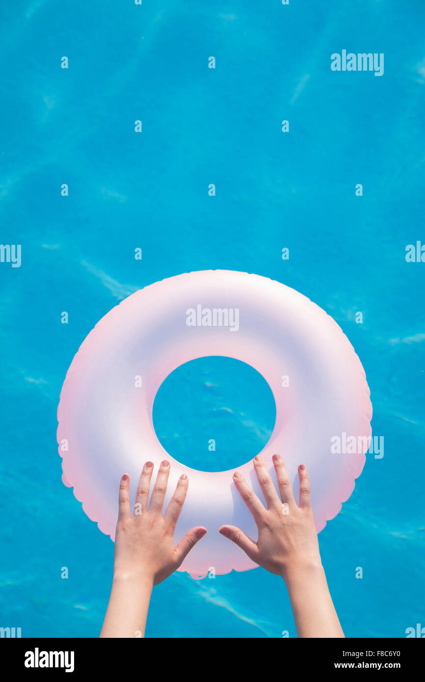 Hohen Winkel der Hände auf rosa aufblasbare Rundrohr schwimmend im pool Stockfoto