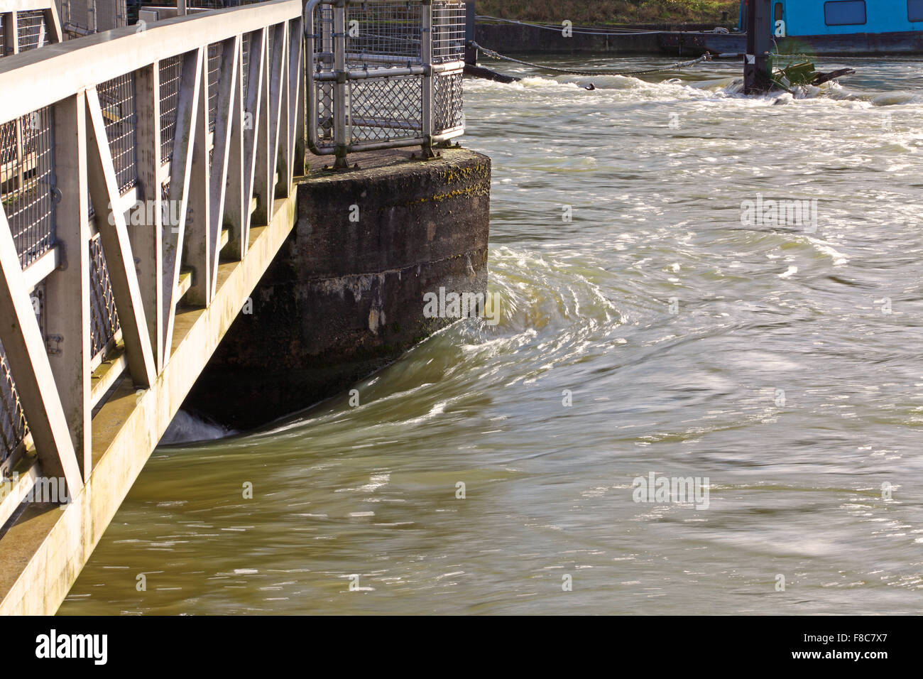 Schnell rauschenden Wasser rund um die Säule ein Wehr zeigt, wie schnell es fließt in den angeschwollenen Fluss fließt. Stockfoto