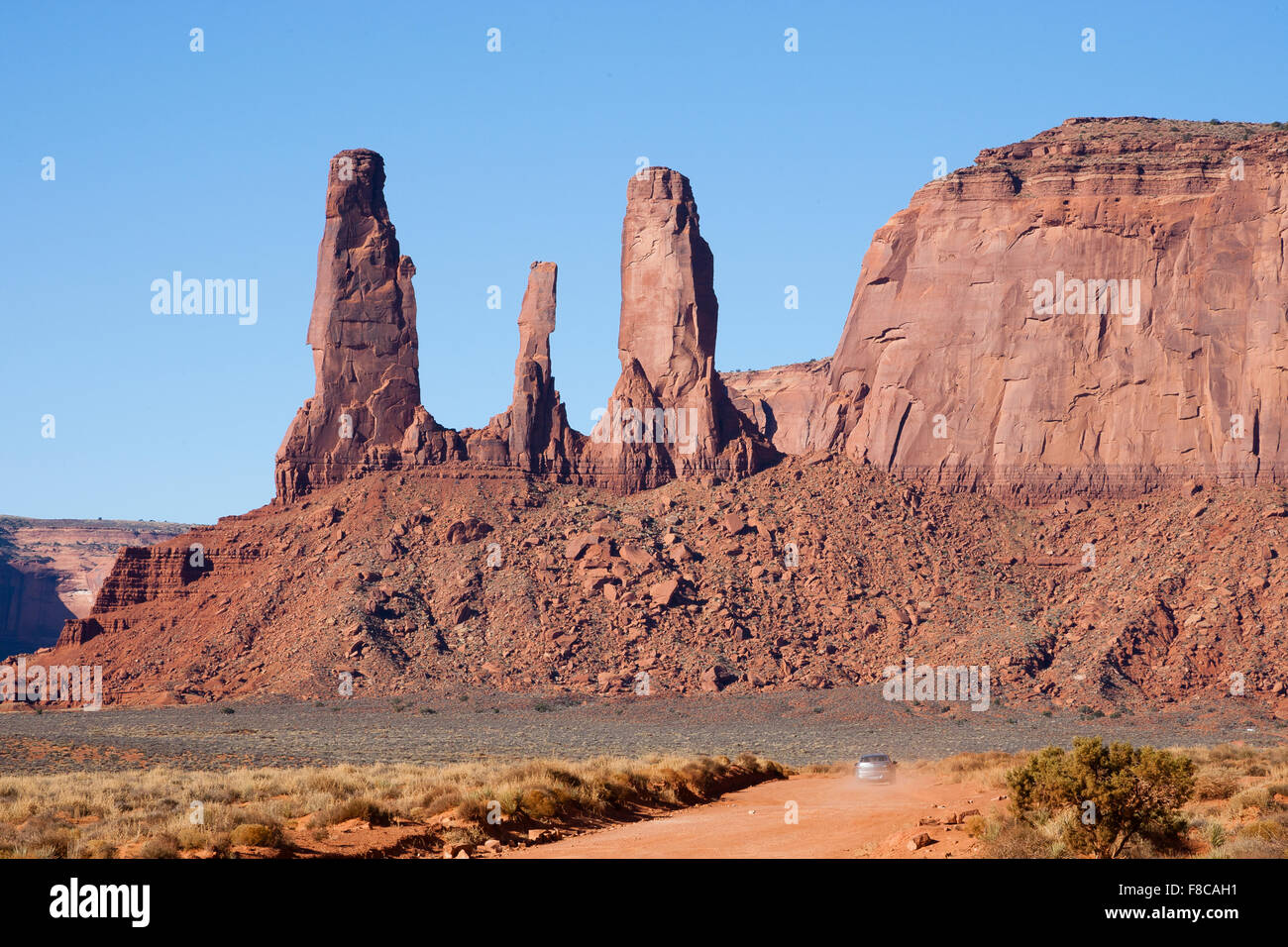 Monument Valley, Arizona. Auto fahren auf unbefestigten Straße mit drei Schwestern Rock im Hintergrund. Stockfoto