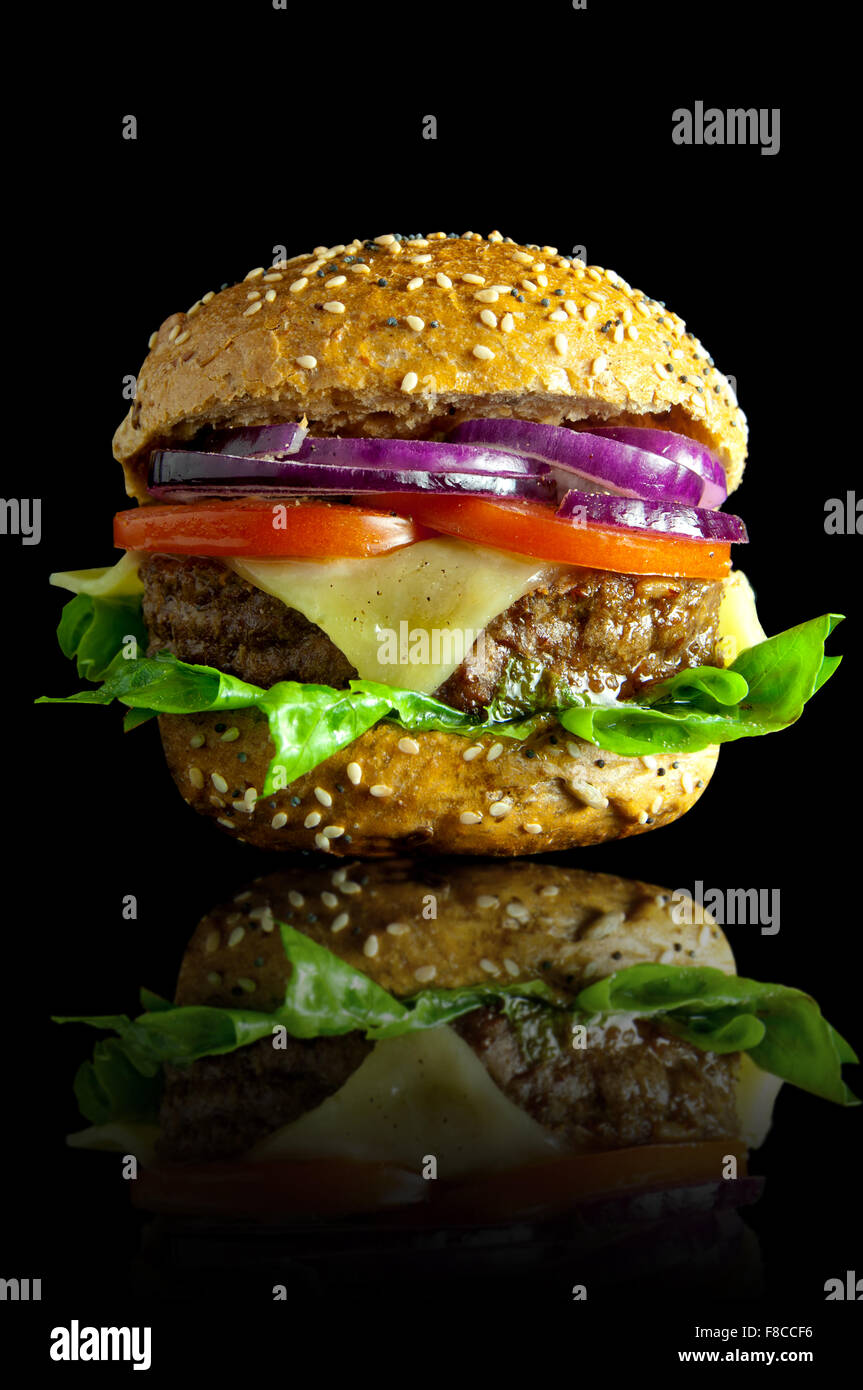 Frisch zubereitete Burger mit geschmolzenem Käse, Zwiebeln, Tomaten und Salat-Füllung Stockfoto