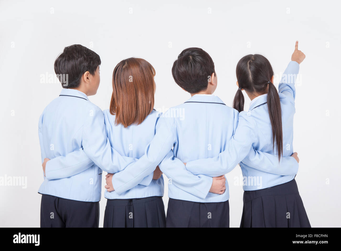 Zurück Darstellung der vier Grundschüler in Schuluniformen, Blick auf die Seite, wo man Mädchen zeigen mit ihren Stockfoto