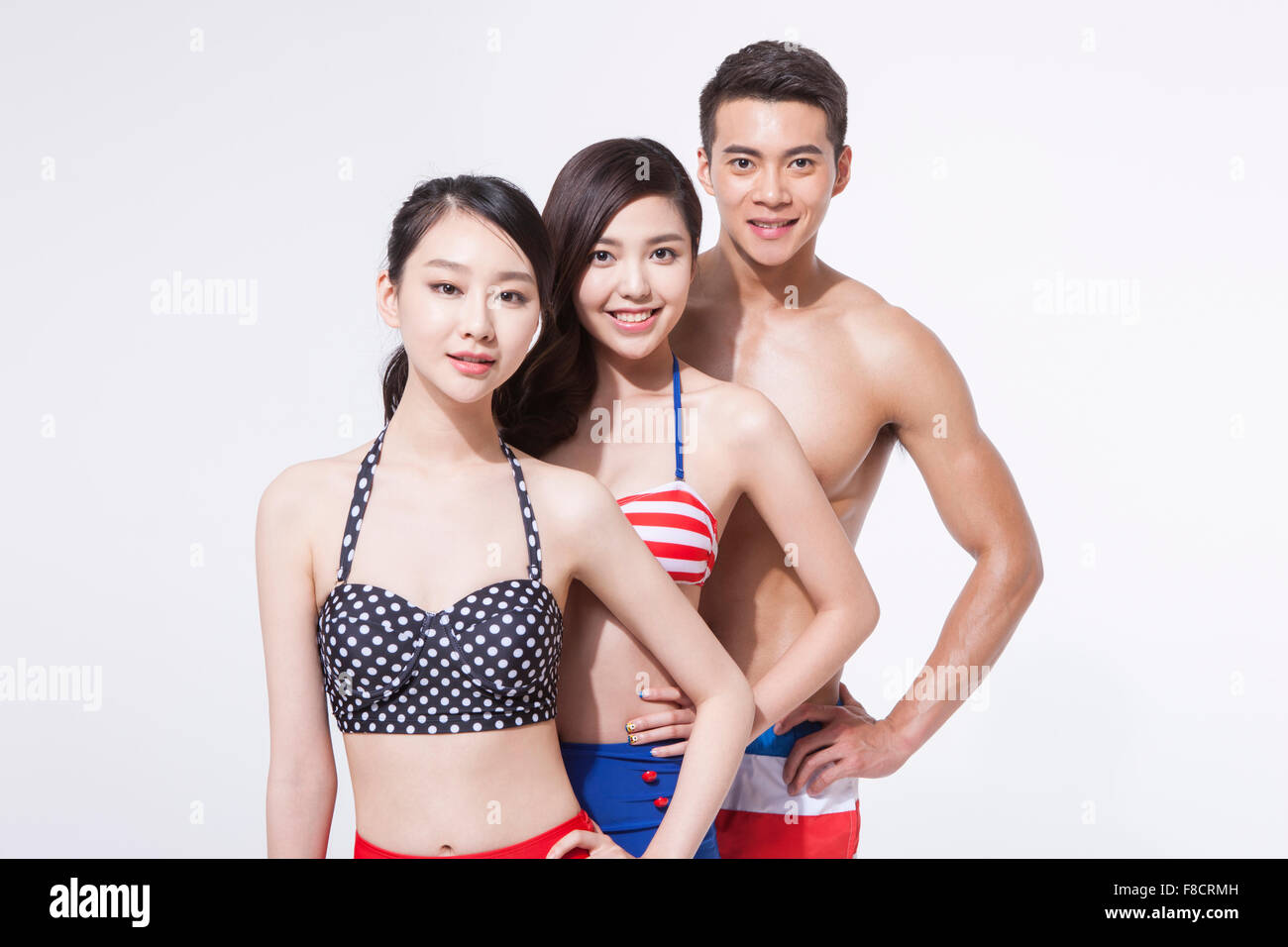 Zwei Frauen im Bikini und ein Mann in Baden Hose in einer Reihe mit einer Hand auf jede Taille starrte mich mit einem Lächeln Stockfoto