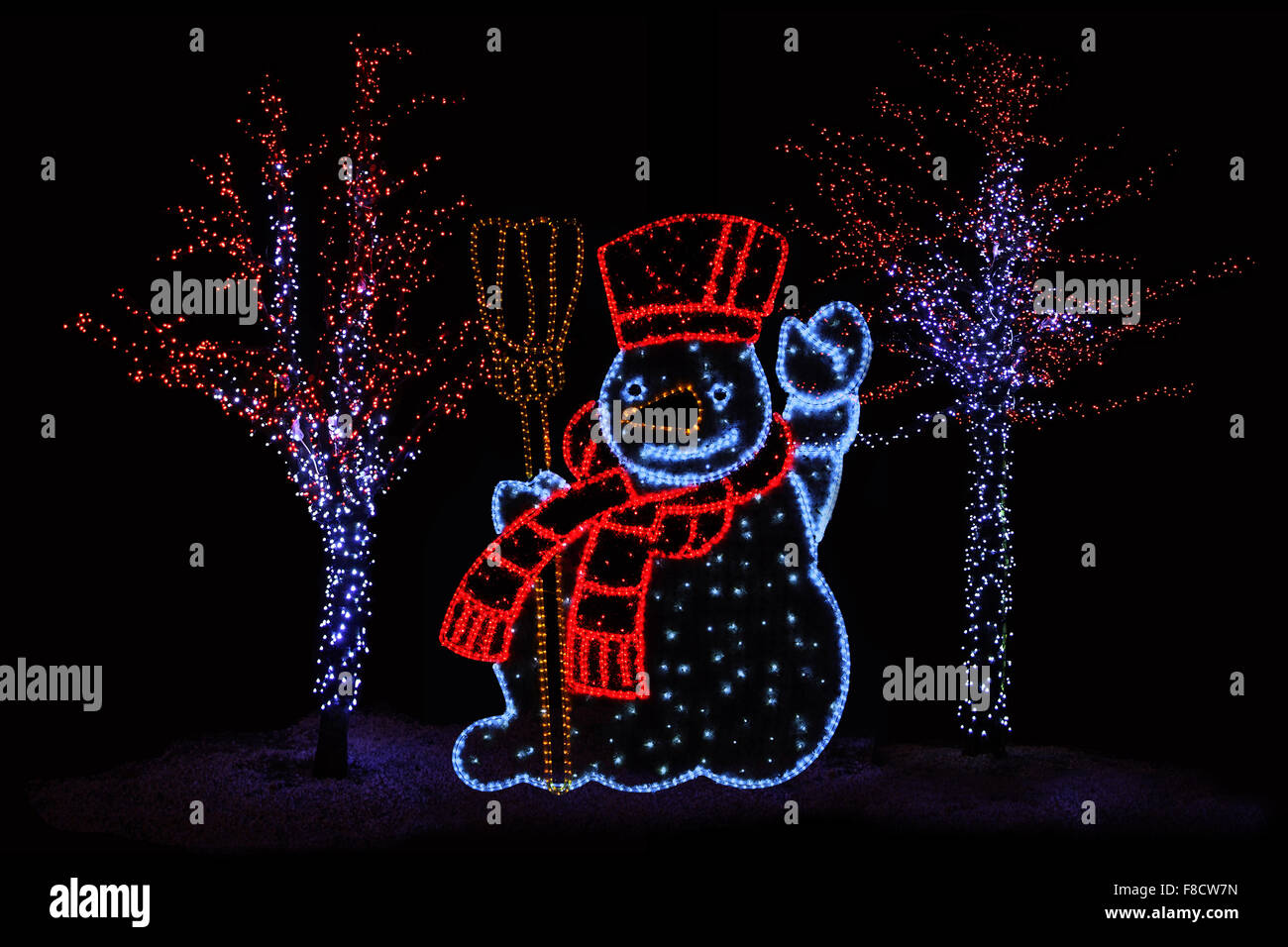 Outdoor-Nachtaufnahme beleuchtete Bäume und Schneemann für die perfekte weihnachtliche Atmosphäre Stockfoto