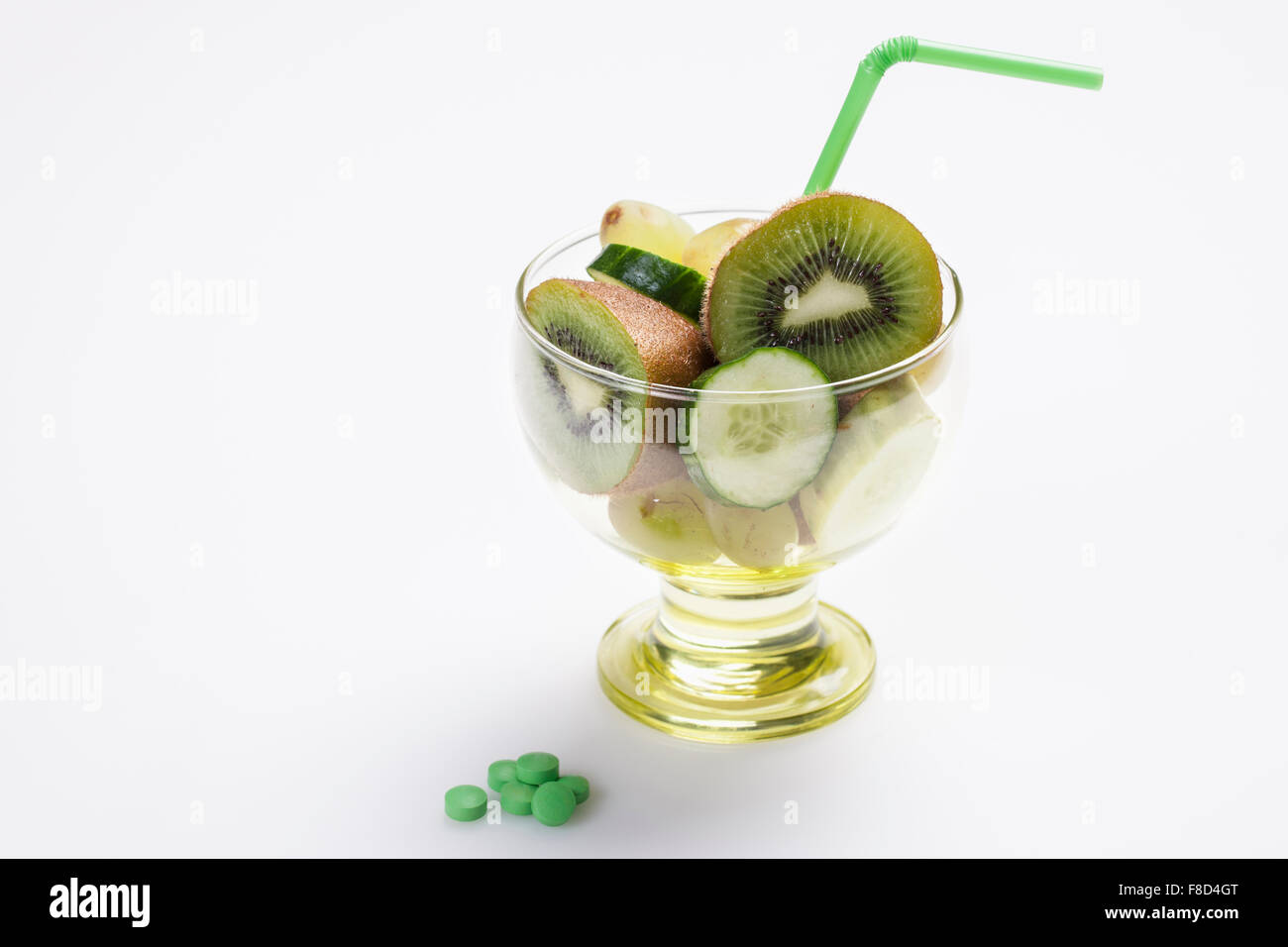 Grüne Farbe Obst und Gemüse Scheiben in ein Glas mit einer Stroh und grünen Farbe Ernährung ergänzt Pillen daneben Stockfoto