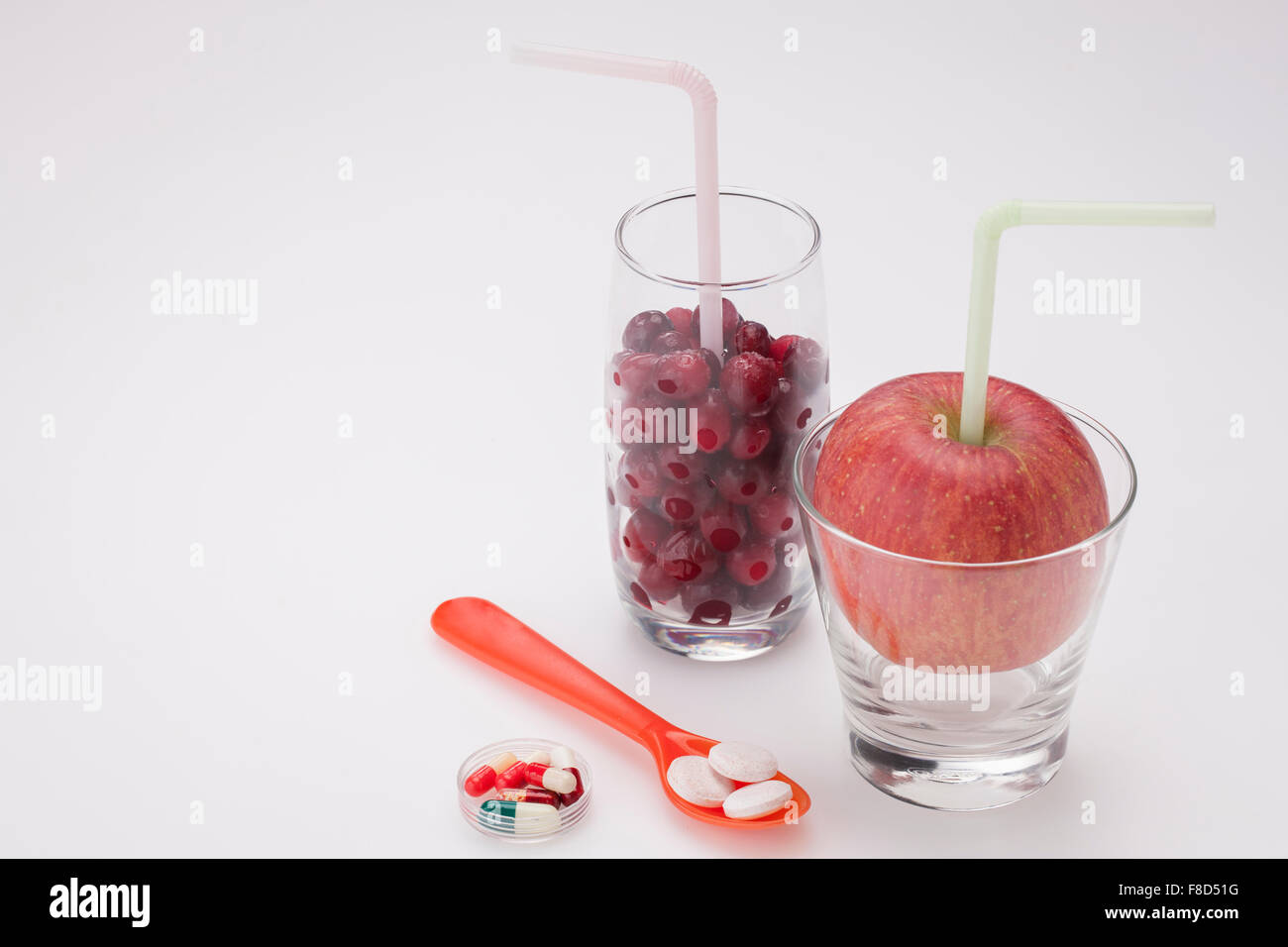 Nahrungsergänzungsmittel in einem Löffel und ein transparenter Behälter mit einem Glas Cranberry und einem Glas einen frischen Apfel mit Stockfoto