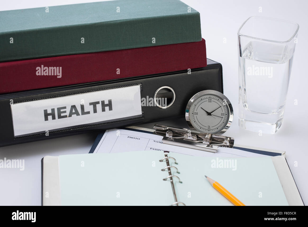 Tagebuch zu öffnen, in einem medizinischen Diagramm mit einer Uhr und einige Dateien neben einem Glas Wasser Stockfoto