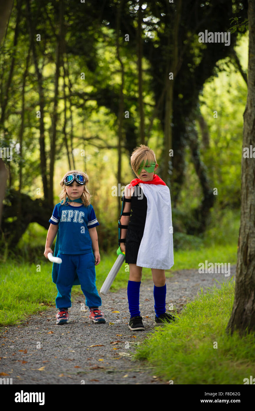 Zwei jungen in hausgemachten Kostümen verkleidet und spielen im Freien, Mini Superhelden an einem Sommerabend, UK Stockfoto