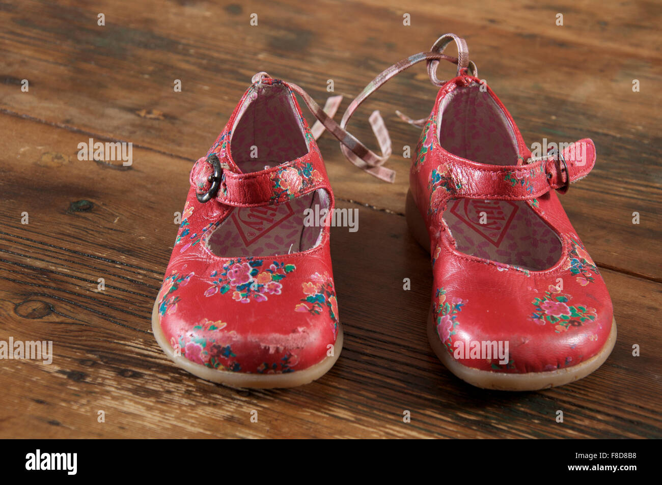 Ein gut getragen paar kleine Mädchen helle rote Schuhe auf einem alten  Holzboden gelegt Stockfotografie - Alamy