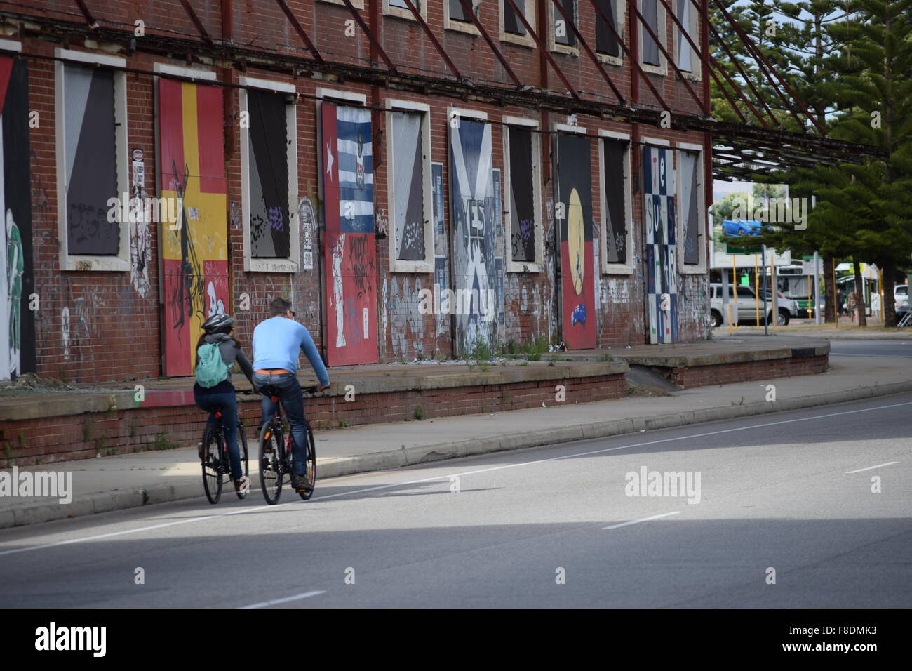 Radfahrer fahren vorbei an der Front der alten Wolle Läden in Fremantle, Western Australia Stockfoto