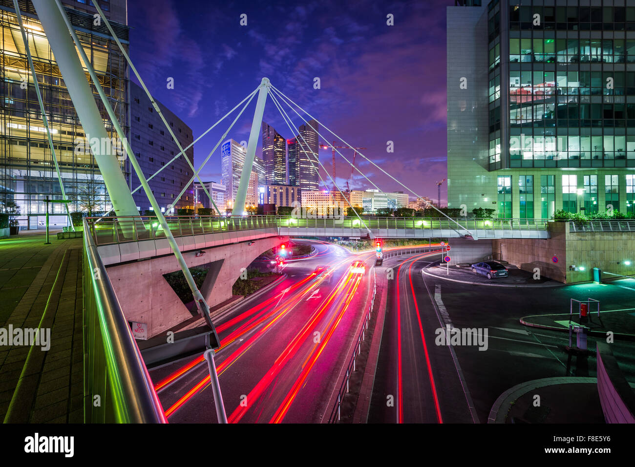 Fußgängerbrücke und moderne Gebäude neben einer Straße in der Nacht in La Défense in Paris, Frankreich. Stockfoto