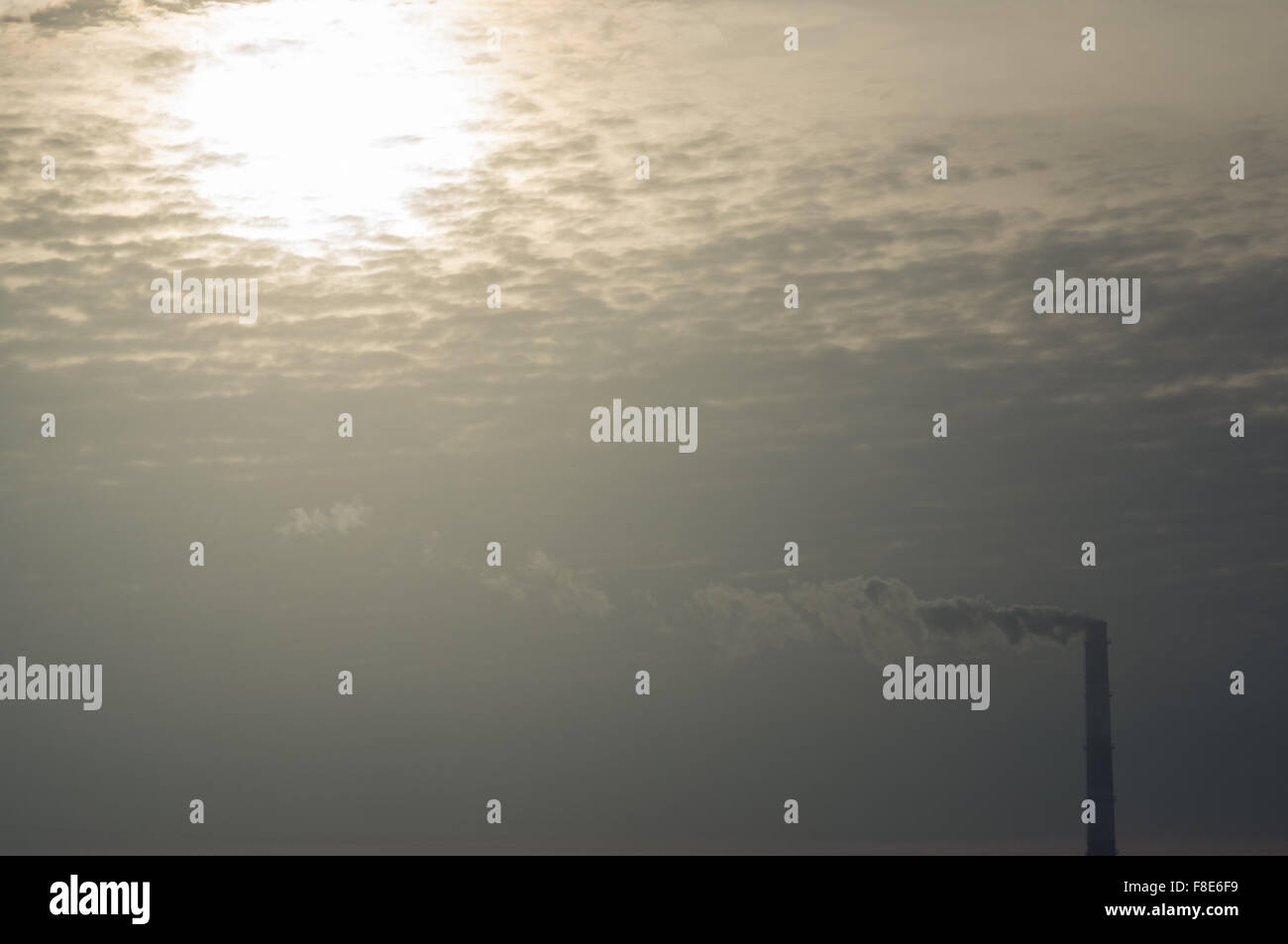 Dampf aus Schornstein gegen Morgensonne und Wolken Stockfoto