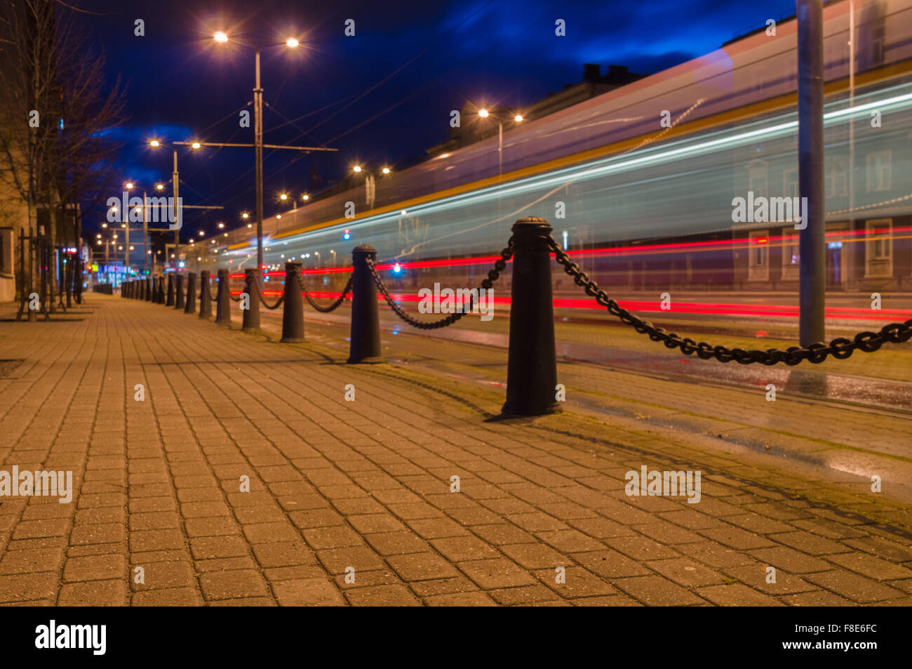 Spur des Lichts hinterlassen mit der Straßenbahn in der Nacht. Gepflasterte Straße mit dekorativen Stöcke und Kette Stockfoto