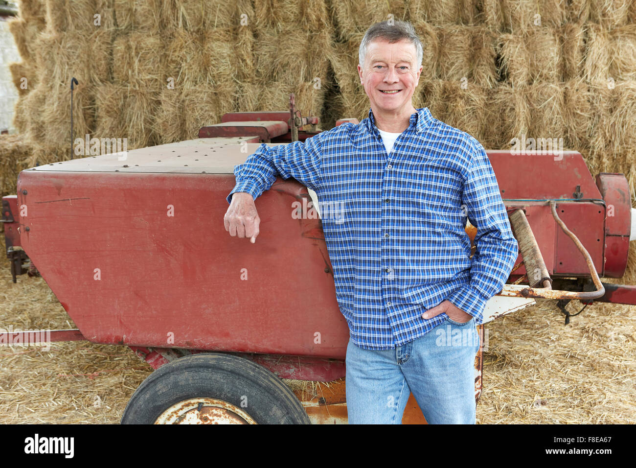 Landwirt vor Ballen und alte Landmaschinen Stockfoto