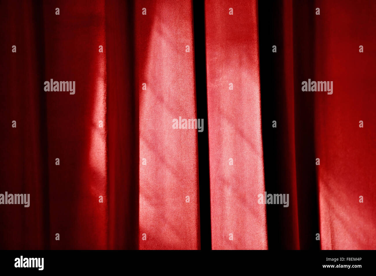 Nahaufnahme mit Sonnenlicht fällt auf einen roten Theatervorhang erschossen Stockfoto