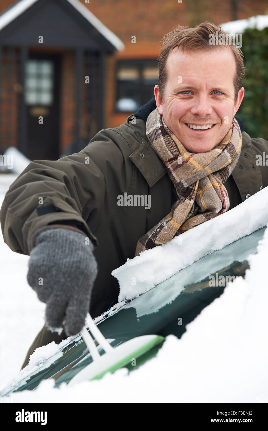 Mann, Schnee vom Auto Windschutzscheibe kratzen Stockfoto