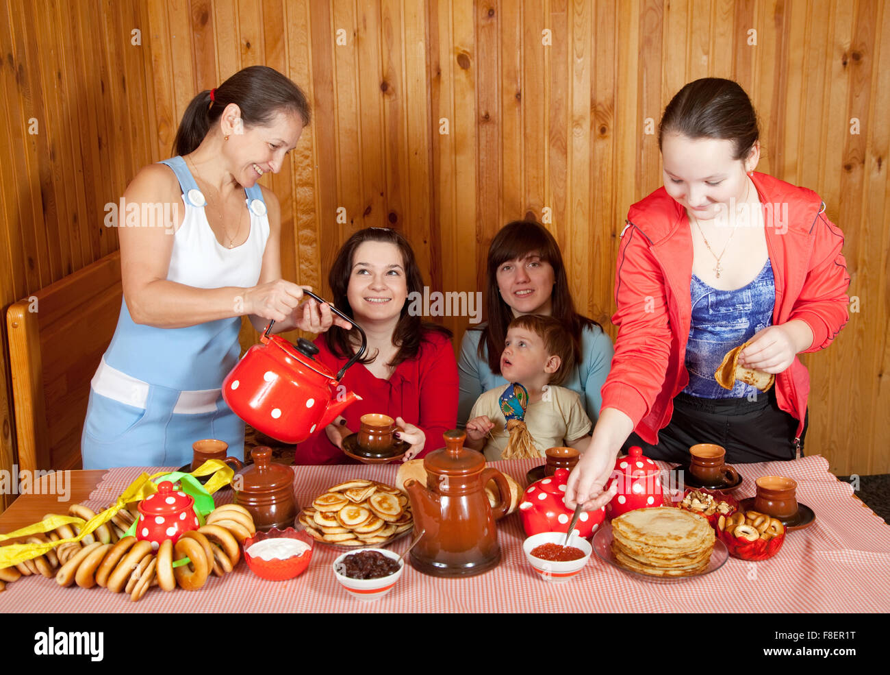 Frauen mit Kind trinkt Tee und isst Pfannkuchen in Haus Stockfoto
