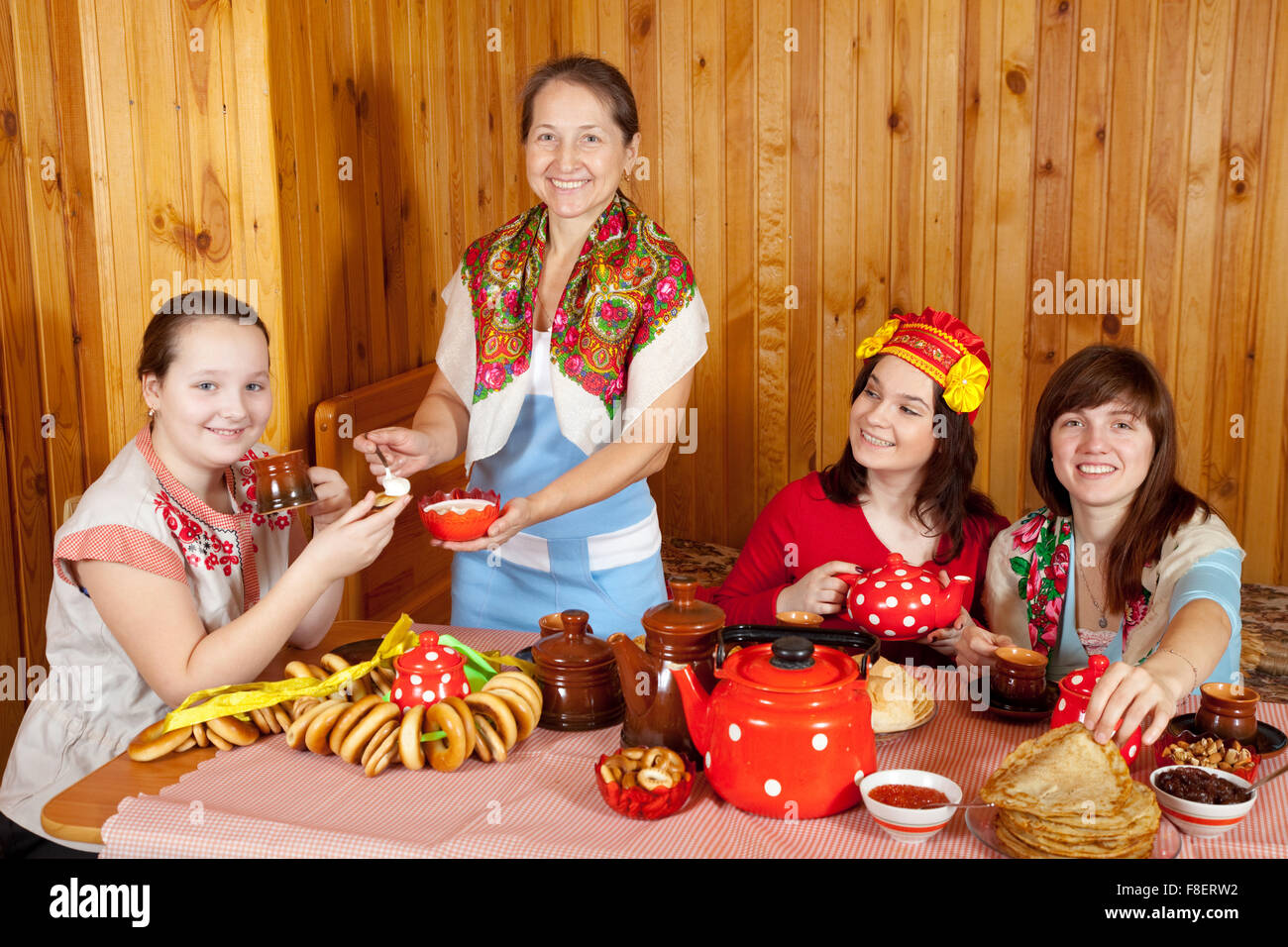 Frauen in traditioneller Kleidung trinkt Tee und isst Pfannkuchen Stockfoto