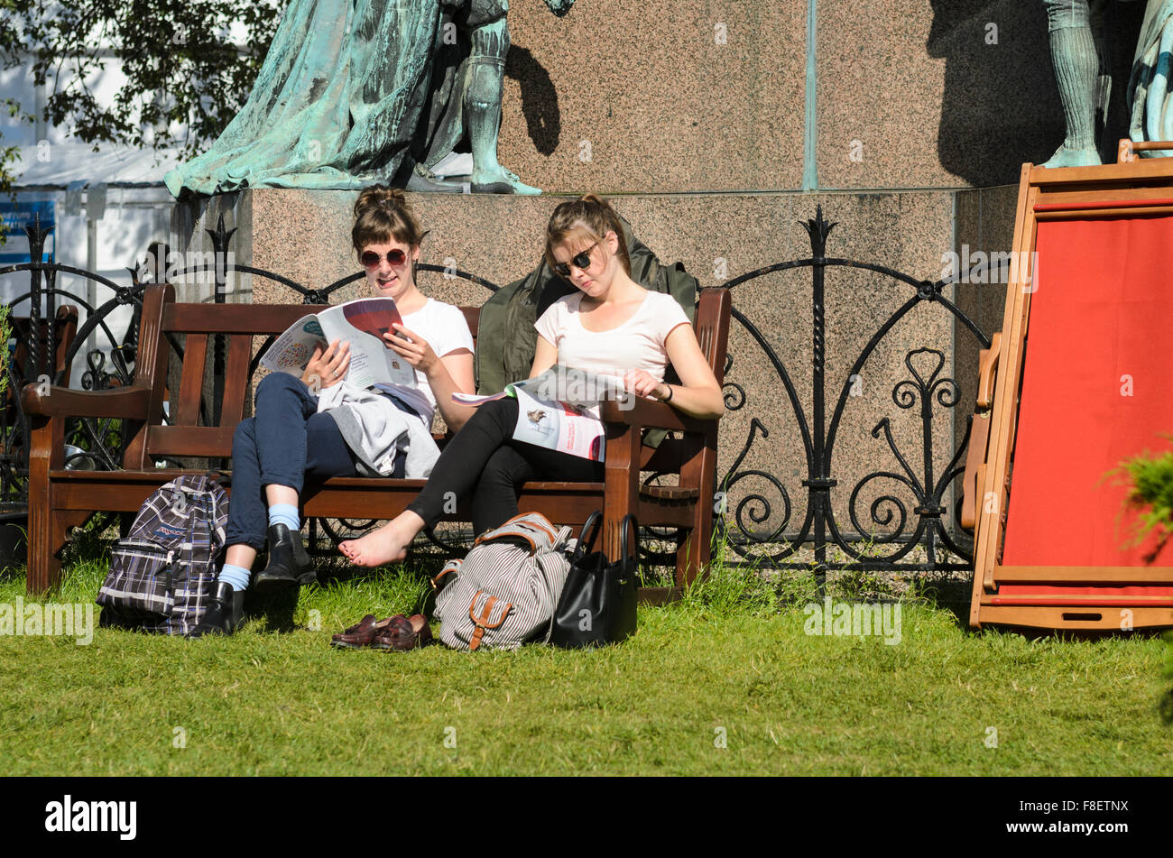 Zwei junge Frau in der Sonne entspannen beim Lesen des Programms für das Jahr 2015 Edinburgh International Book Festival. Stockfoto
