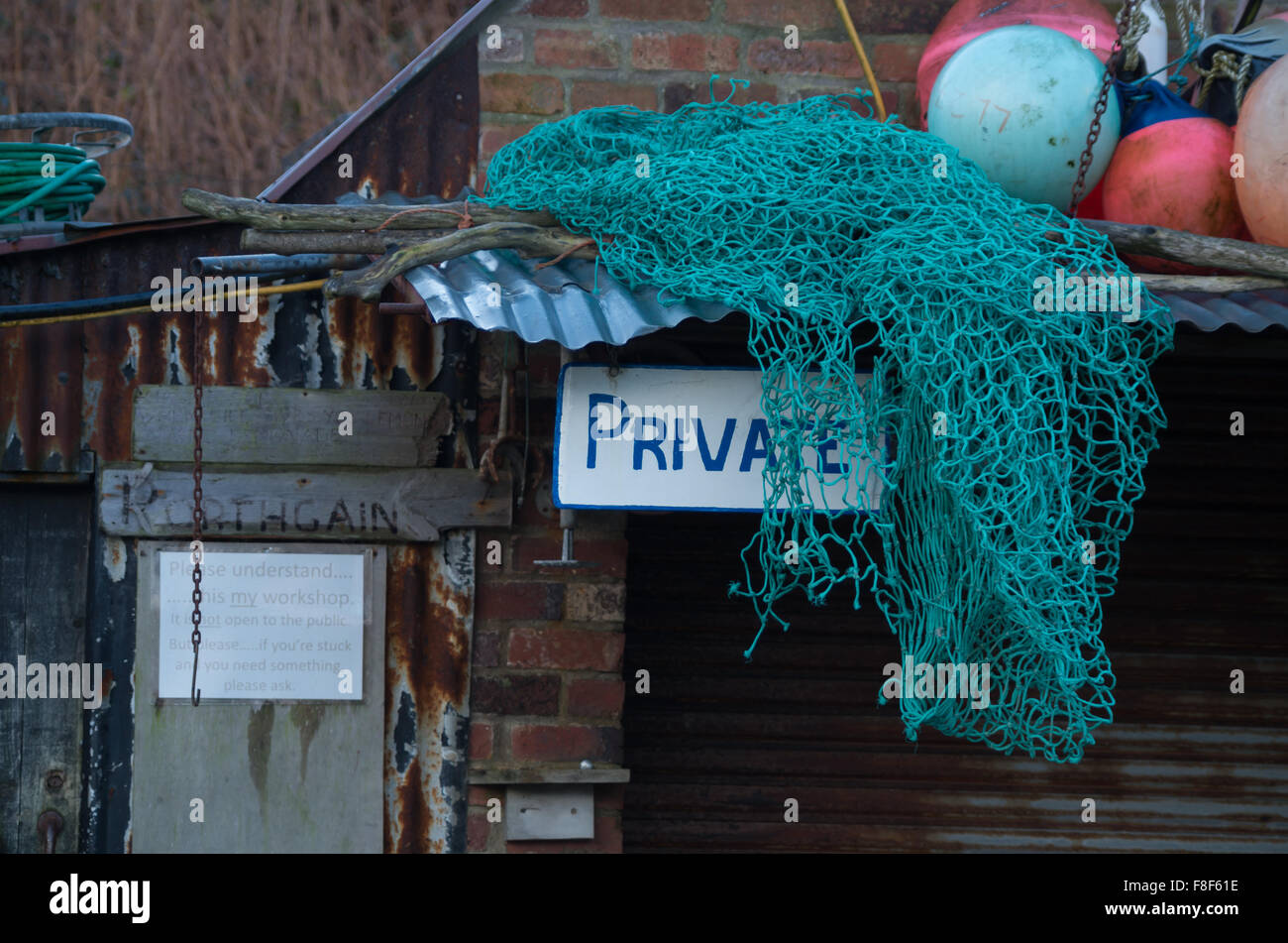 'Private' Schild mit Fischernetz und Bojen auf Blechdach. Stockfoto