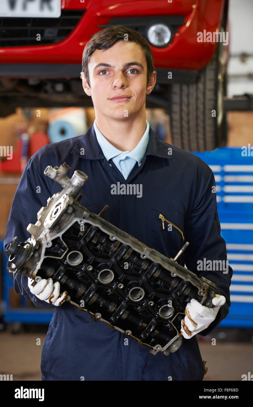 Lehrling Machanic hält Motorblock In Garage Stockfoto