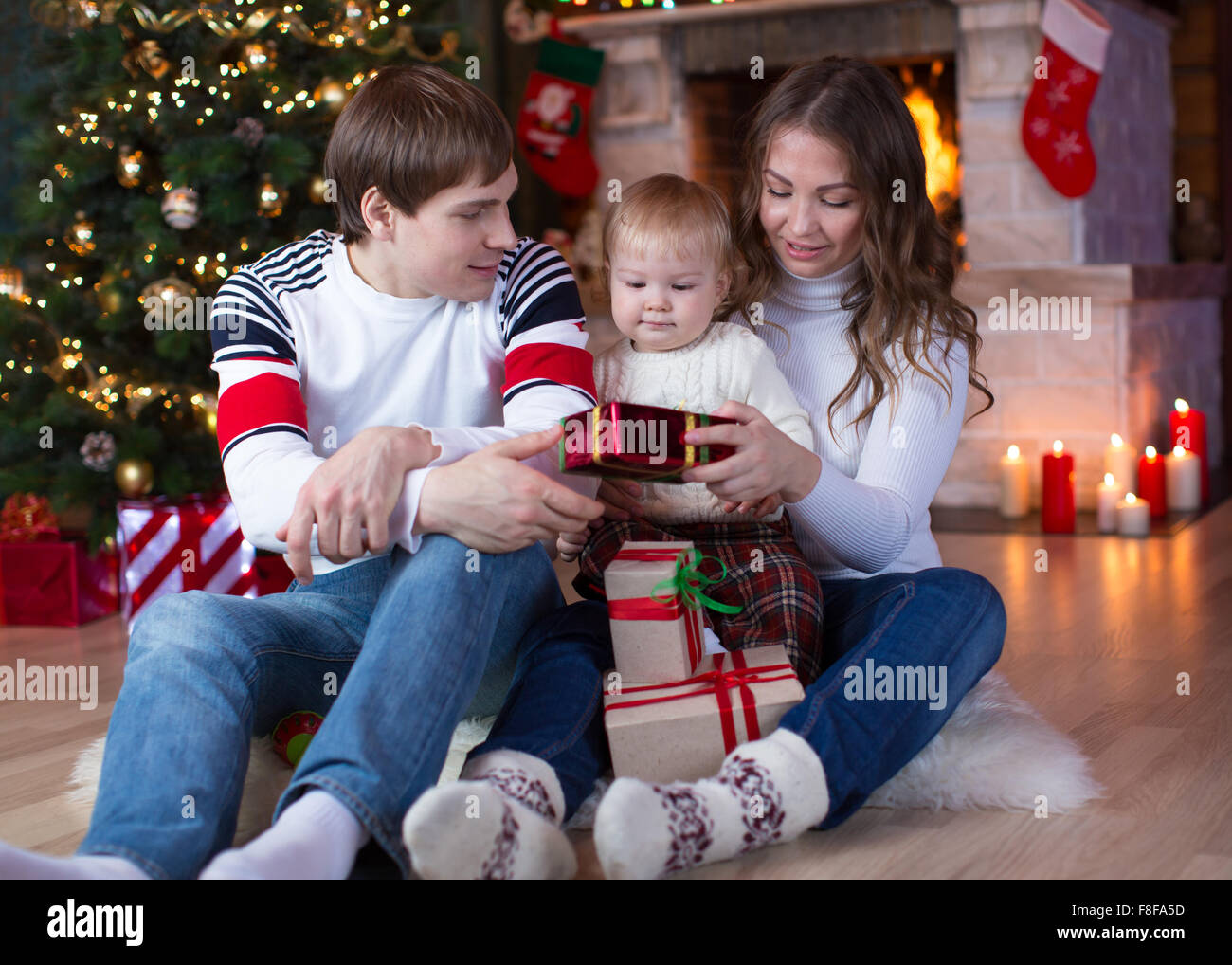 Glückliche Familie mit Geschenken am Weihnachtsbaum in der Nähe von Kamin sitzen Stockfoto