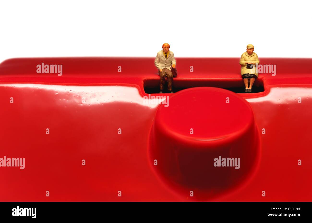Zwei Miniatur alt Alter Rentner sitzen auf eine rote Spardose Stockfoto